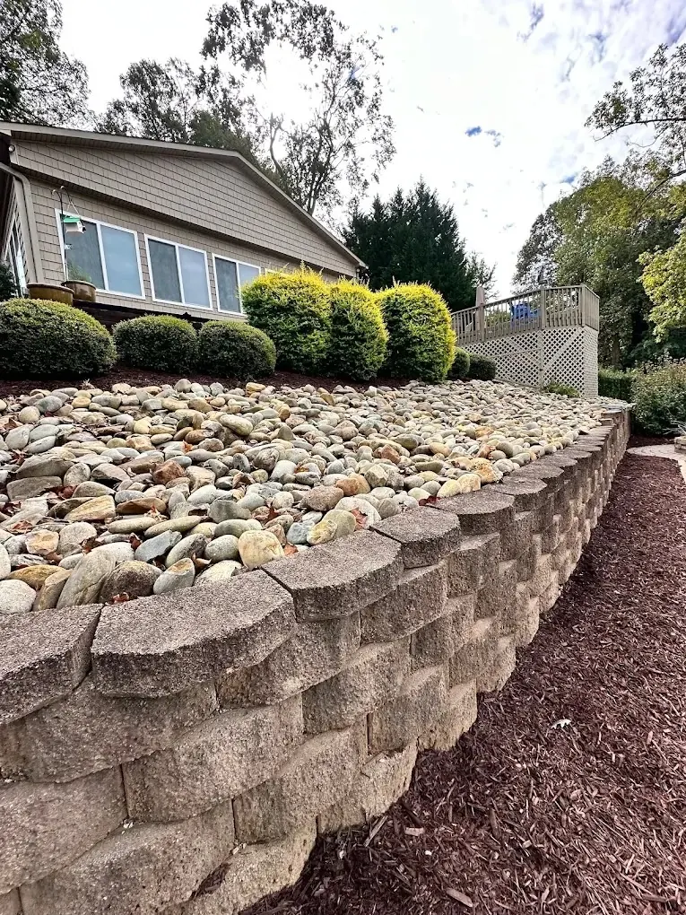 A finished retaining wall with river rock and planting
